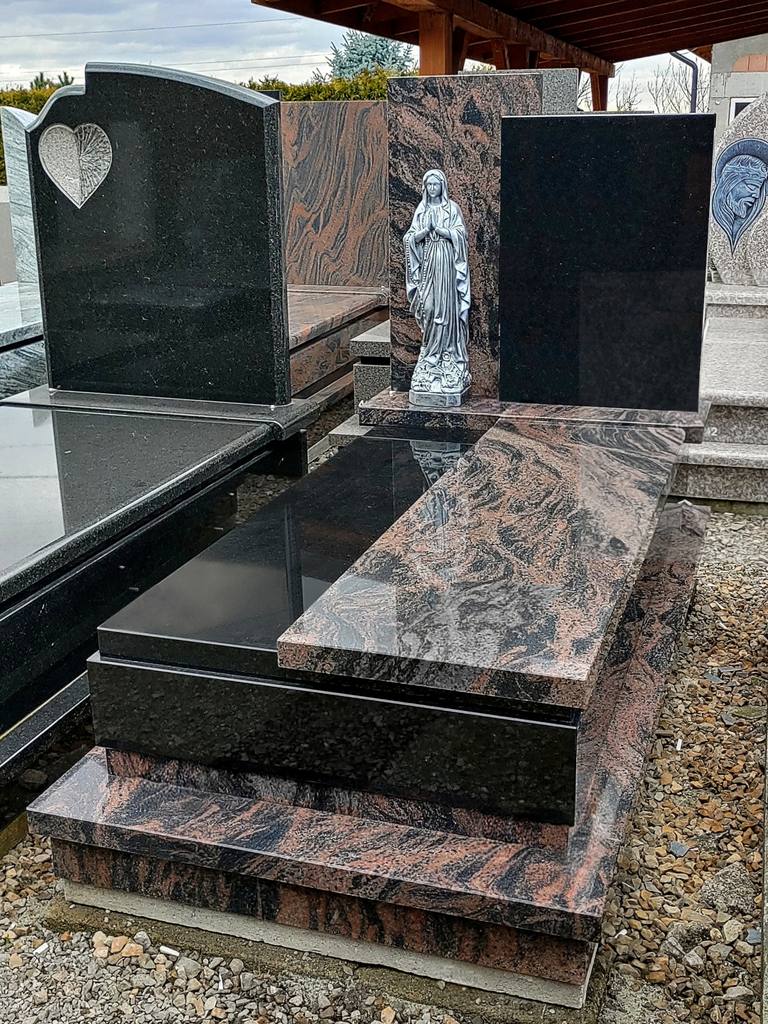 Nagrobek pojedynczy z kamienia "Aurora" i "Warangal" z asymetryczną tablicą, wykończeniem w kantach oraz srebrną figurą Matki Bożej