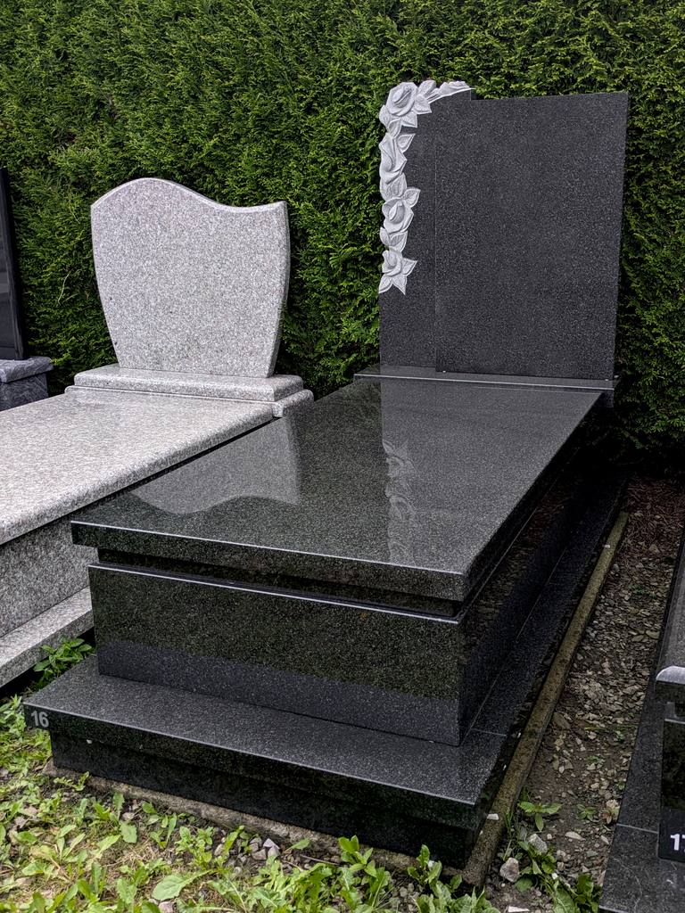 Nagrobek z ciemnego kamienia z rzeźbionymi różami