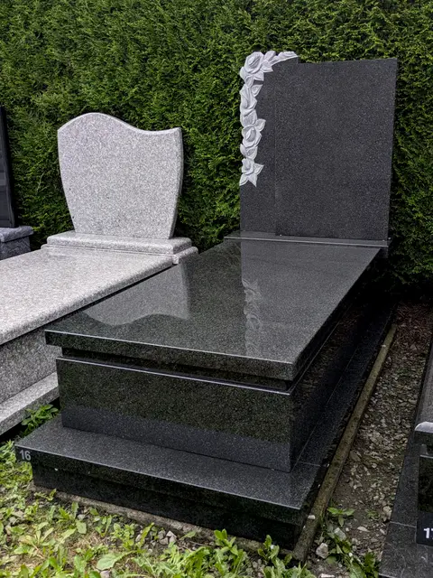 Nagrobek z ciemnego kamienia z rzeźbionymi różami