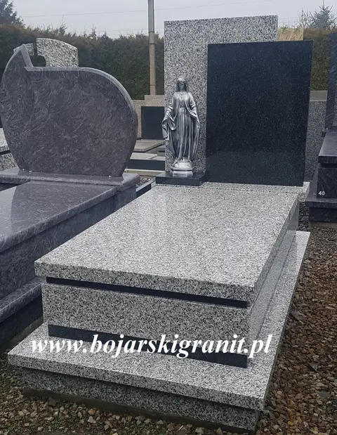 Nagrobek z granitu "Bianco Perla" z ciemną tablicą z granitu "Impala" oraz figurką Matki Boskiej