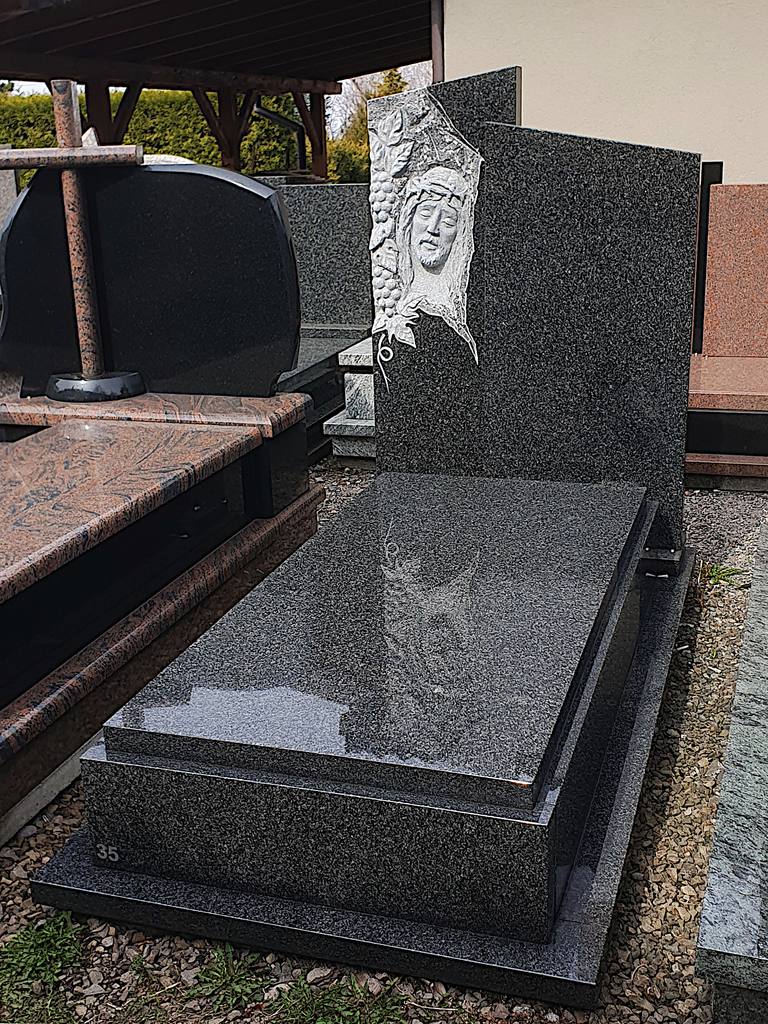 Nowoczesny nagrobek pojedynczy z granitu "Impala" z ręcznie wykonaną płaskorzeźbą Jezusa w koronie cierniowej oraz asymetryczną tablicą