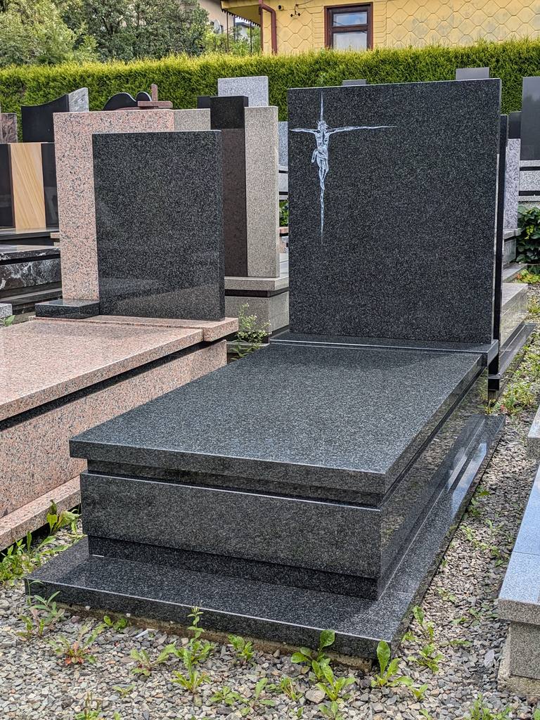 Prosty nagrobek pojedynczy z granitu "Impala" z minimalistyczną płąskorzeźbą Jezusa na krzyżu i wykończeniem w kantach