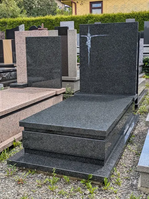 Prosty nagrobek pojedynczy z granitu "Impala" z minimalistyczną płąskorzeźbą Jezusa na krzyżu i wykończeniem w kantach