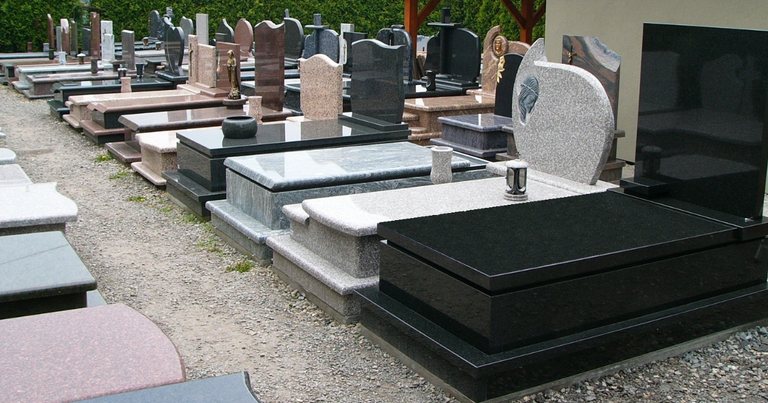 Tradycyjny cmentarz z zadbanymi nagrobkami granitowymi w otoczeniu zieleni