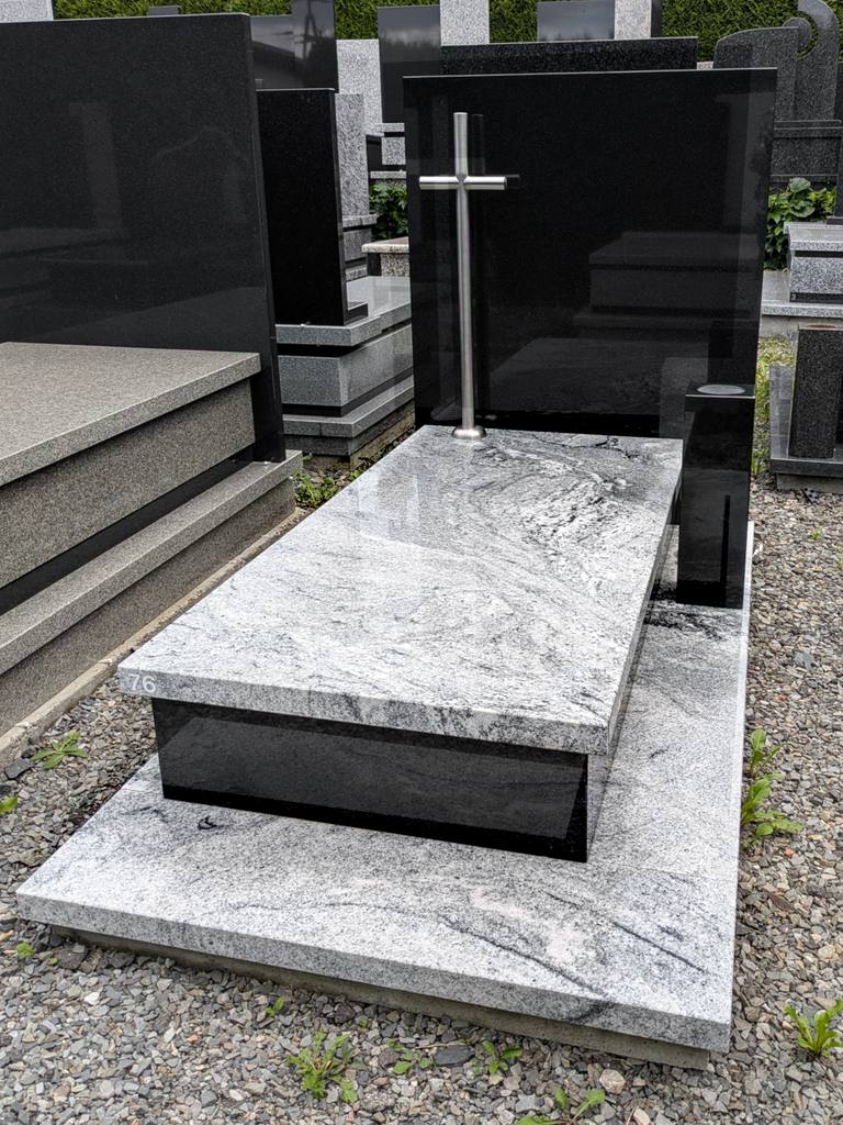 Nowoczesny nagrobek pojedynczy z granitów "Viscount White" i "Warangal Black" ze stojącym krzyżem nierdzewnym oraz kamiennym wazonem